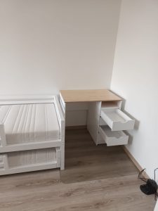 White children's desk with lacquered wooden table top and four drawers with soft close glides and one open shelf.