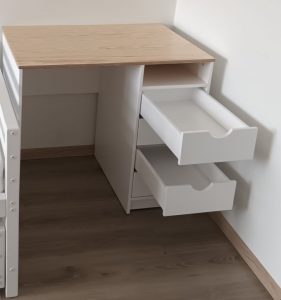 Balts rakstāmgalds bērniem ar lakotu koka galda virsmu un četrām atvilktnēm ar soft close vadotņu mehānismu un vienu atvērtu plauktu.