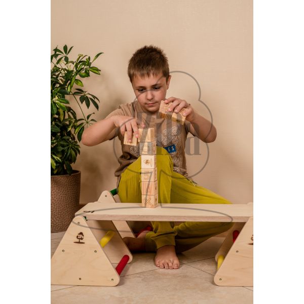 Bērns spēlējas ar alfabēta klucīšiem uz balansa konstruktora