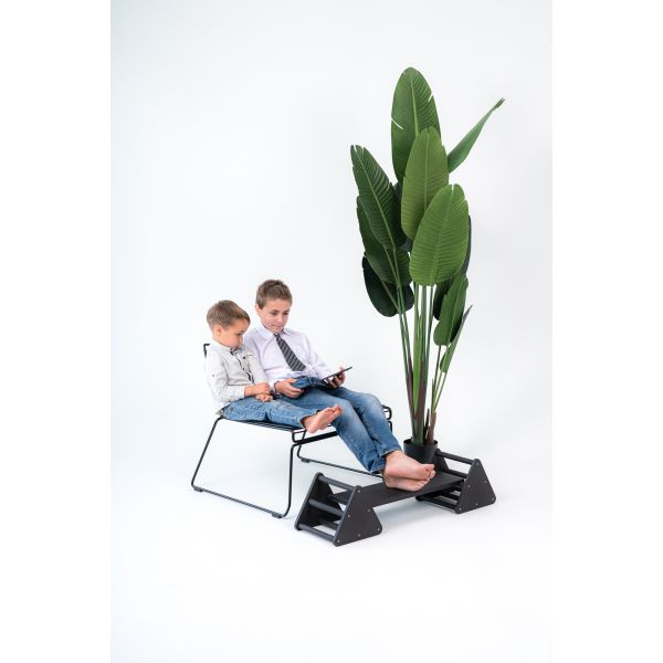 Balance constructor, black. Board in middle position. Two boys use a balance constructor as a footrest.