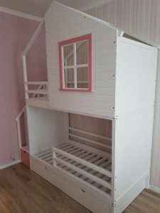 Divstāvu gulta ar rozā lodziņu un podesta atvilktnēm. Divstāvu mājiņgulta divās krāsās. Bērnu gulta ar jumtu un lodziņu.