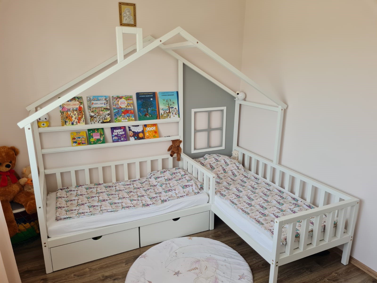 L-shape bed with window and shelves, right corner. White L-shape bed with grey accent wall. Bed for two children with thick, canted slats. Photo of the nursery at client's.